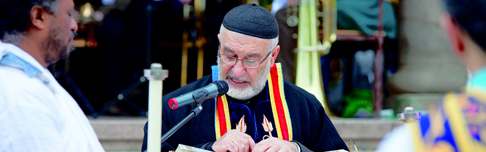 Geistlicher in religiöser Kleidung liest aus einem Buch an einem Pult.