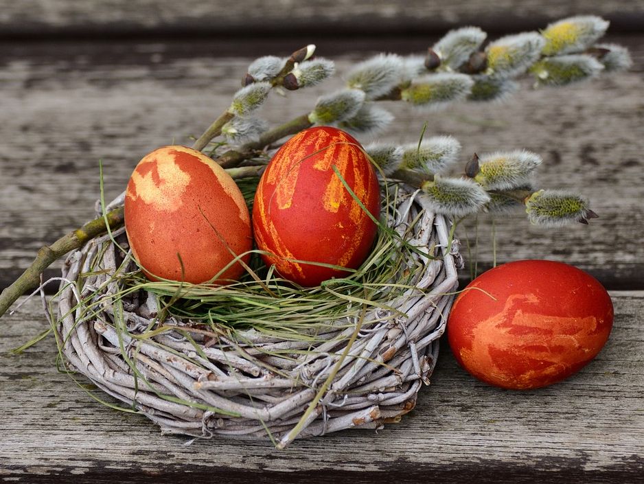 Drei orange bemalte Eier in einem Strohnest