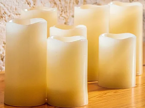 Mehrere weiße, brennende Kerzen auf einem Tisch