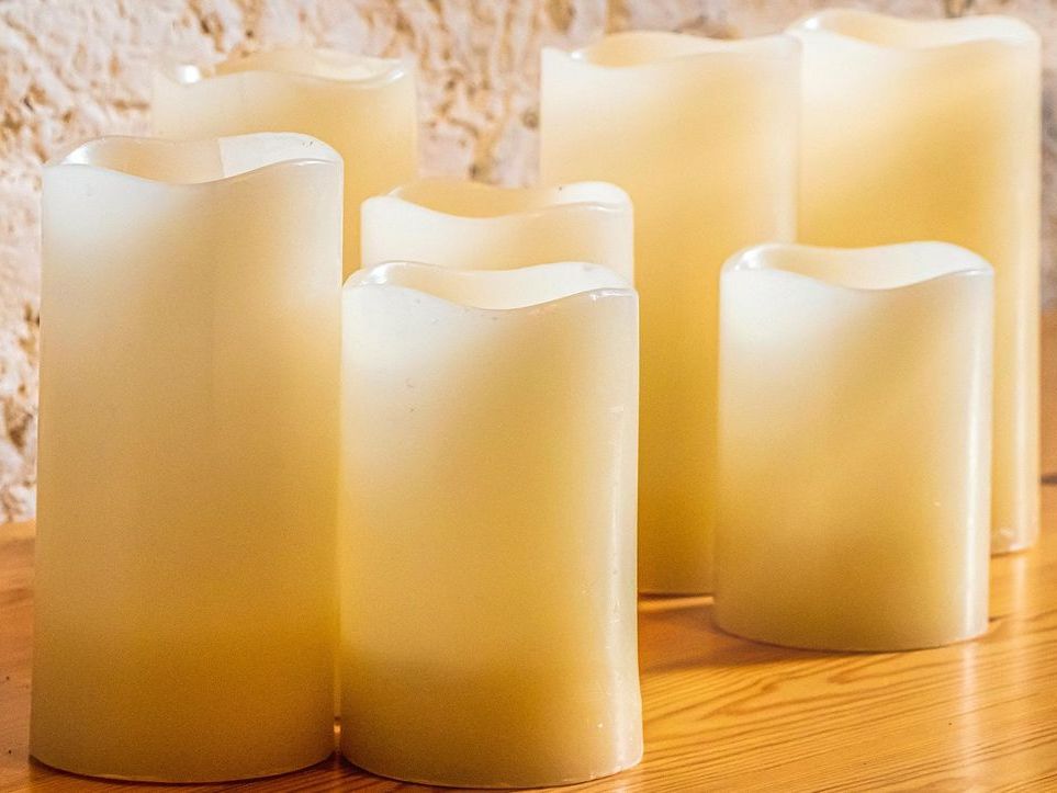 Mehrere weiße, brennende Kerzen auf einem Tisch