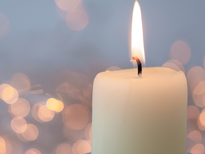 Brennende weiße Kerze mit Lichtpunkten