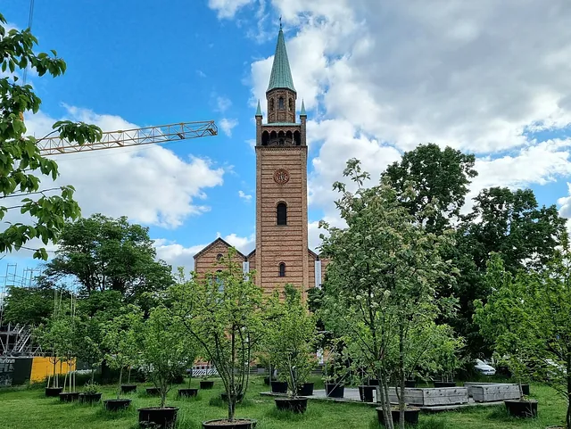 St. Matthäus-Kirche von Wiese und Töpfen mit jungen Bäumen umgeben