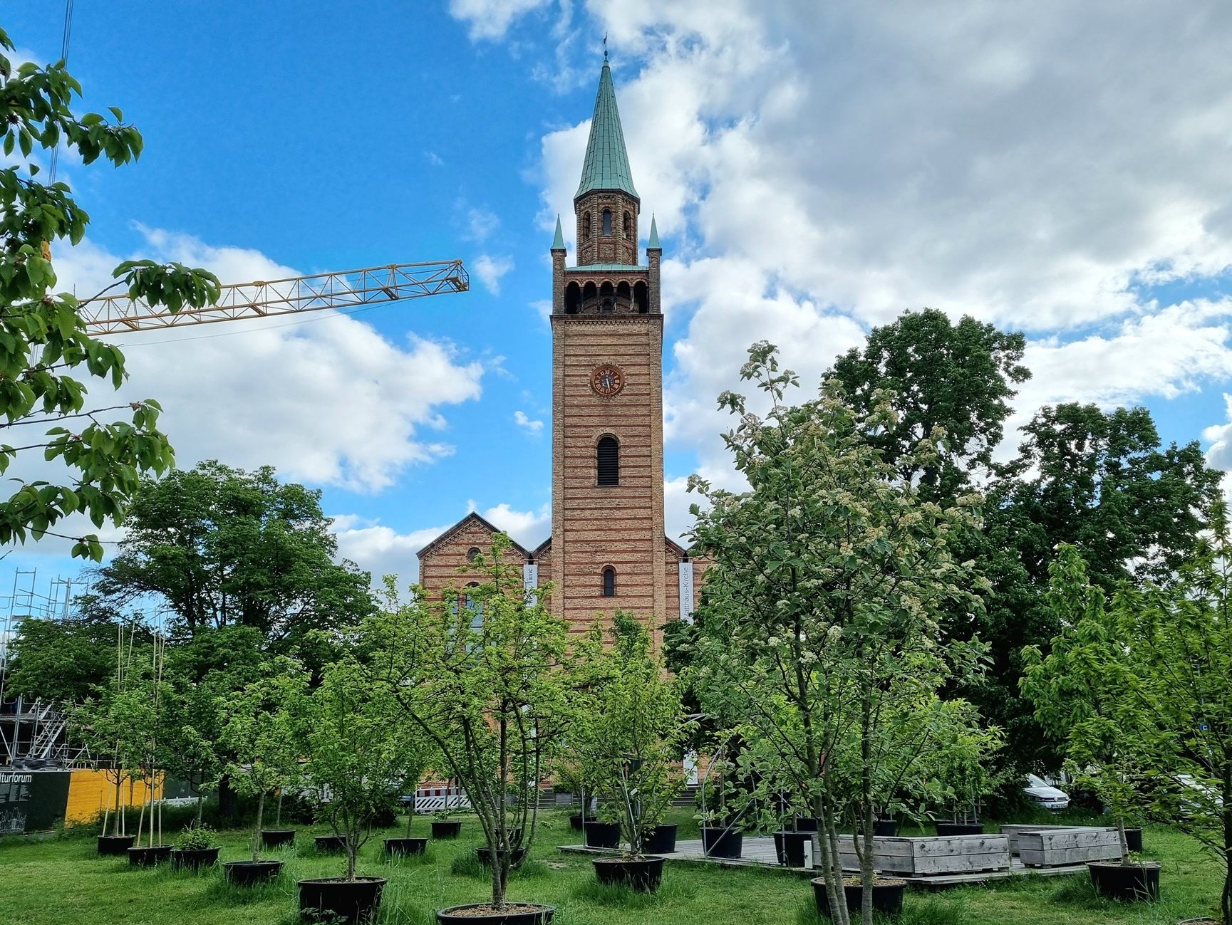 St. Matthäus-Kirche von Wiese und Töpfen mit jungen Bäumen umgeben