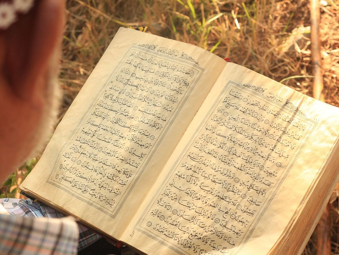 Kleines Mädchen liest auf dem Friedhof aus dem Koran