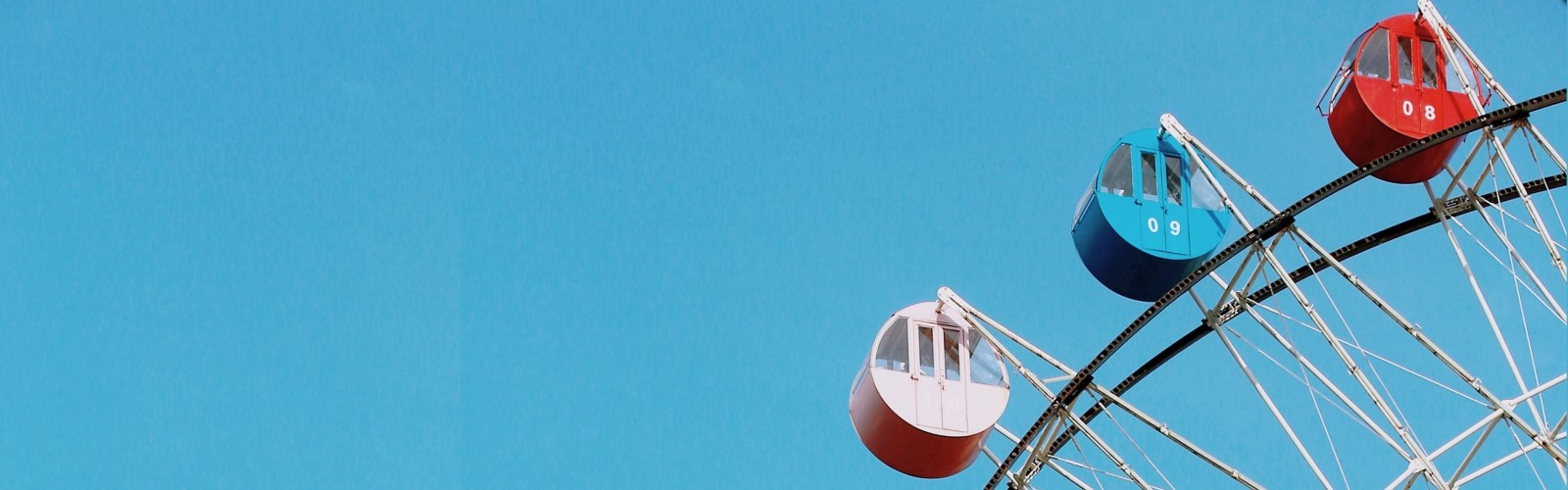 Ausschnitt aus einem Riesenrad, im Hintergrund blauer Himmel