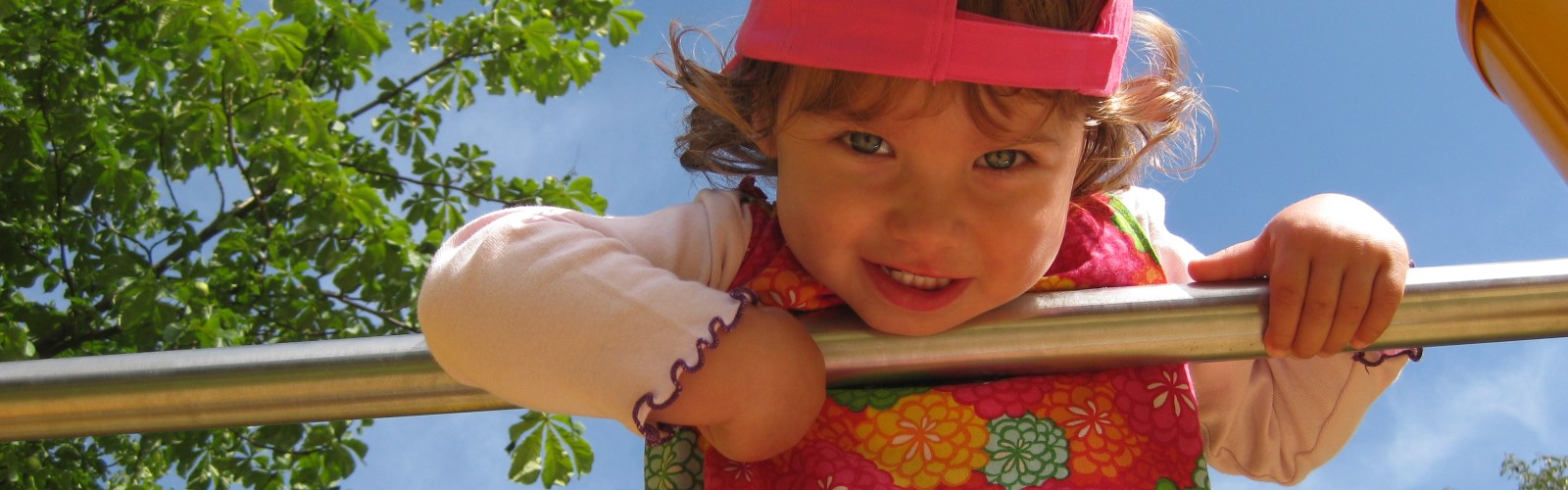 Kleines Mädchen hält sich an einer Stange fest und lächelt