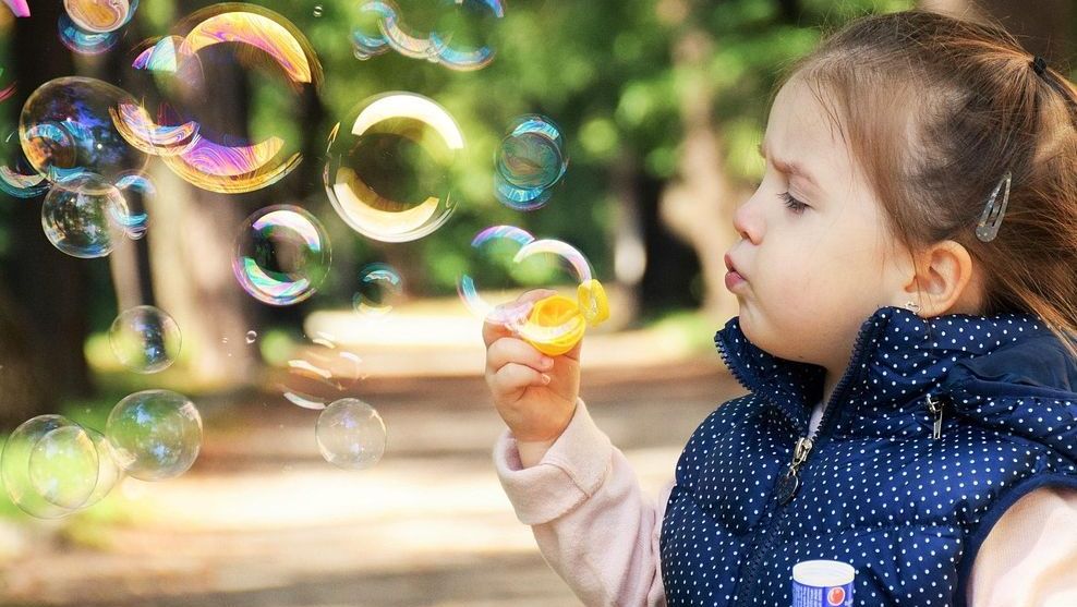 Mädchen pustet Seifenblasen im Park