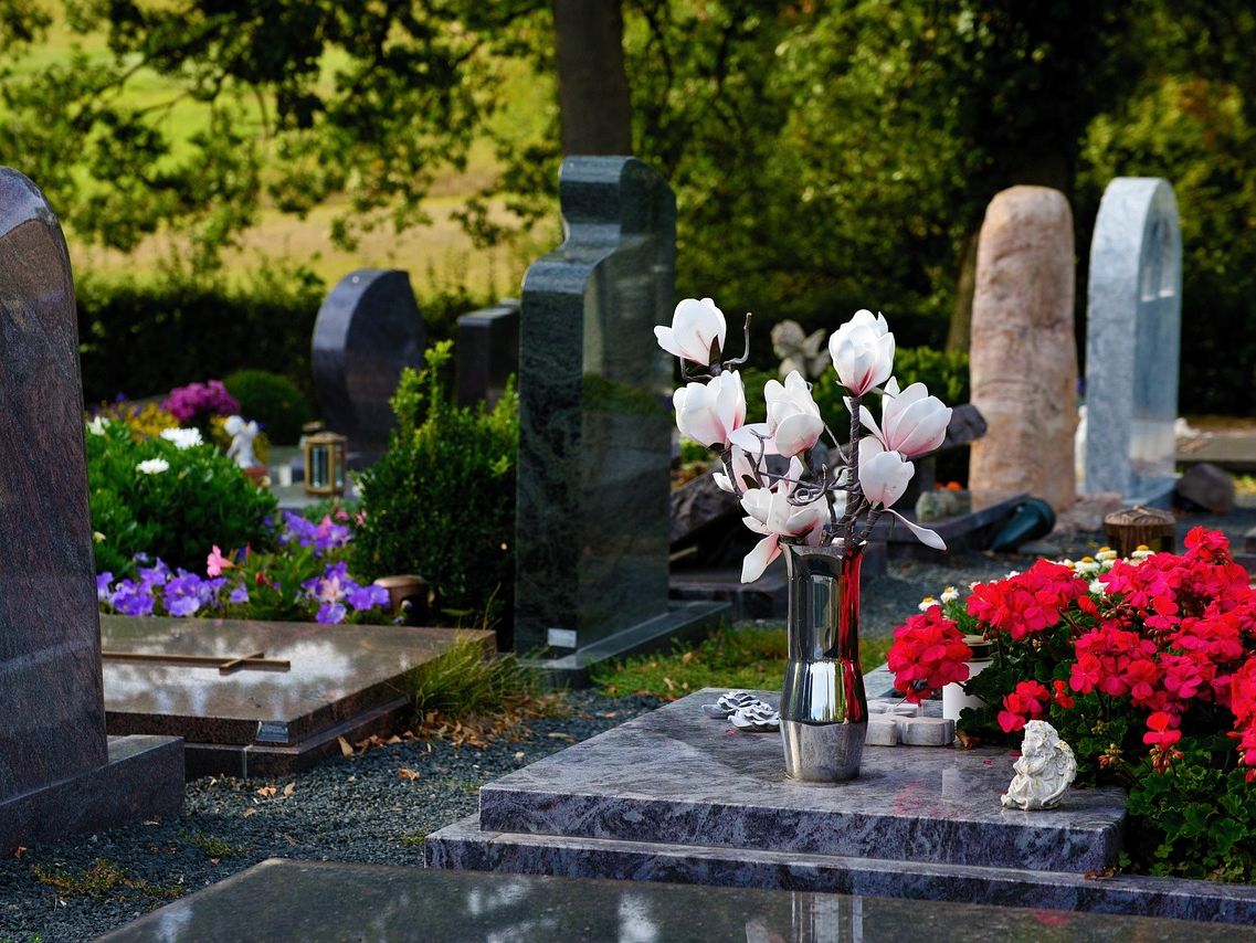 Grabsteine auf einem Friedhof mit Blumenschmuck